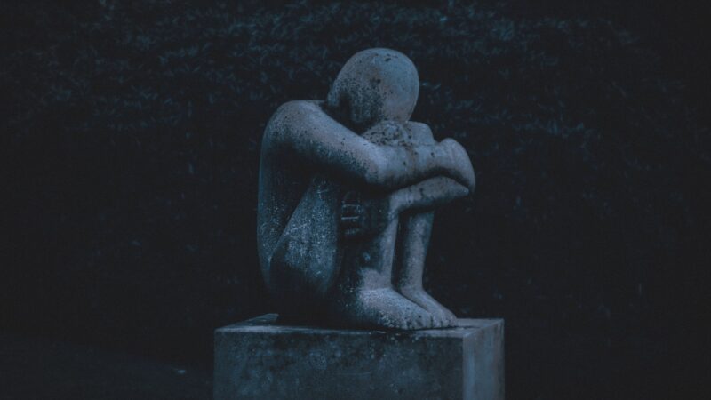 depression in statue hugging knees to chest.